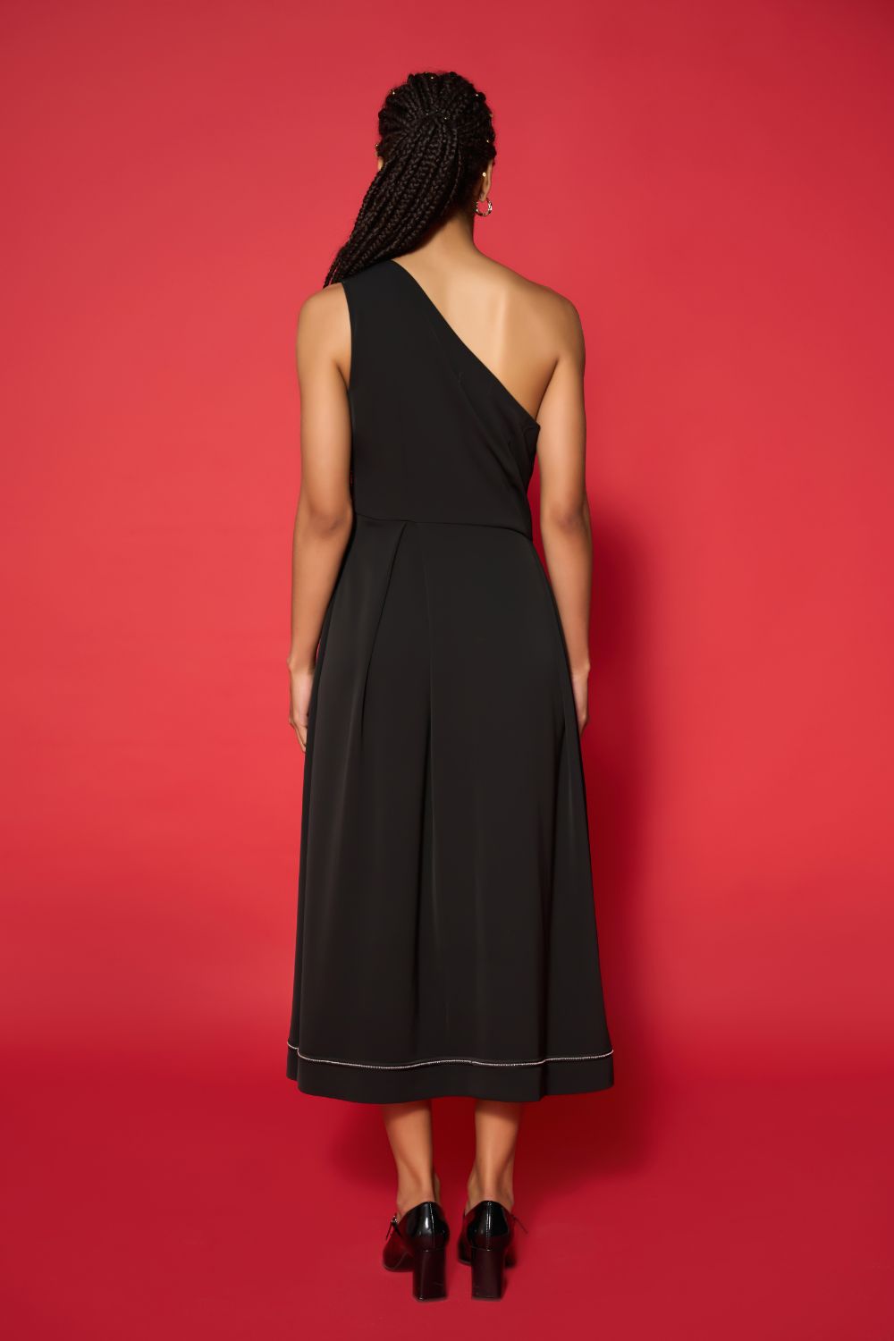 Woman wearing a black one-shoulder dress against a red background