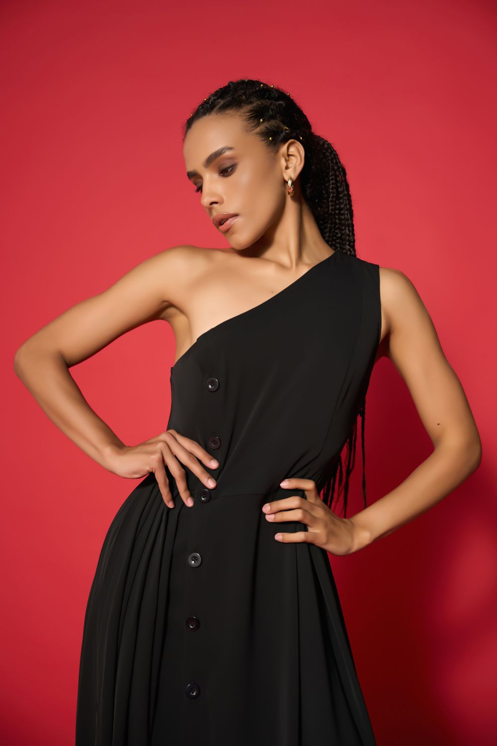 Woman wearing a black one-shoulder dress against a red background