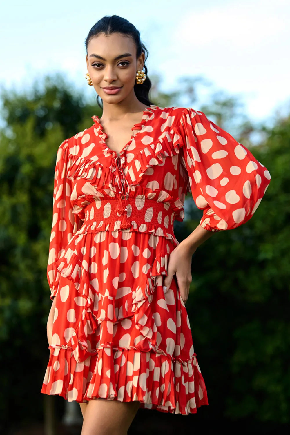 Izia Dress women's coral red Viscose Georgette mini dress featuring a playful white polka dot print, a tie-up neckline with beaded tassels and delicate ruffle detailing, styled for summer brunches, beach holidays, vacation outings and casual daytime gatherings.