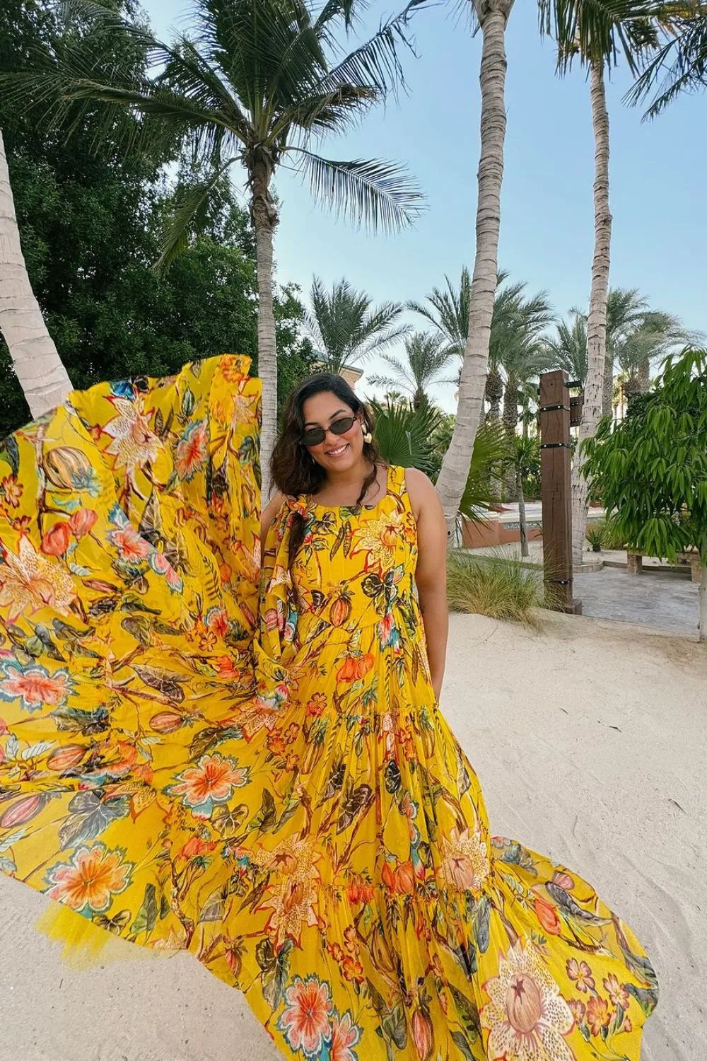 Sakshi Sindwani wearing the Eona Dress, a women's yellow organza midi dress featuring a vibrant multicolour print, romantic tiered skirt and airy flowing silhouette, styled for summer brunches, garden parties, resort holidays and festive daytime celebrations.