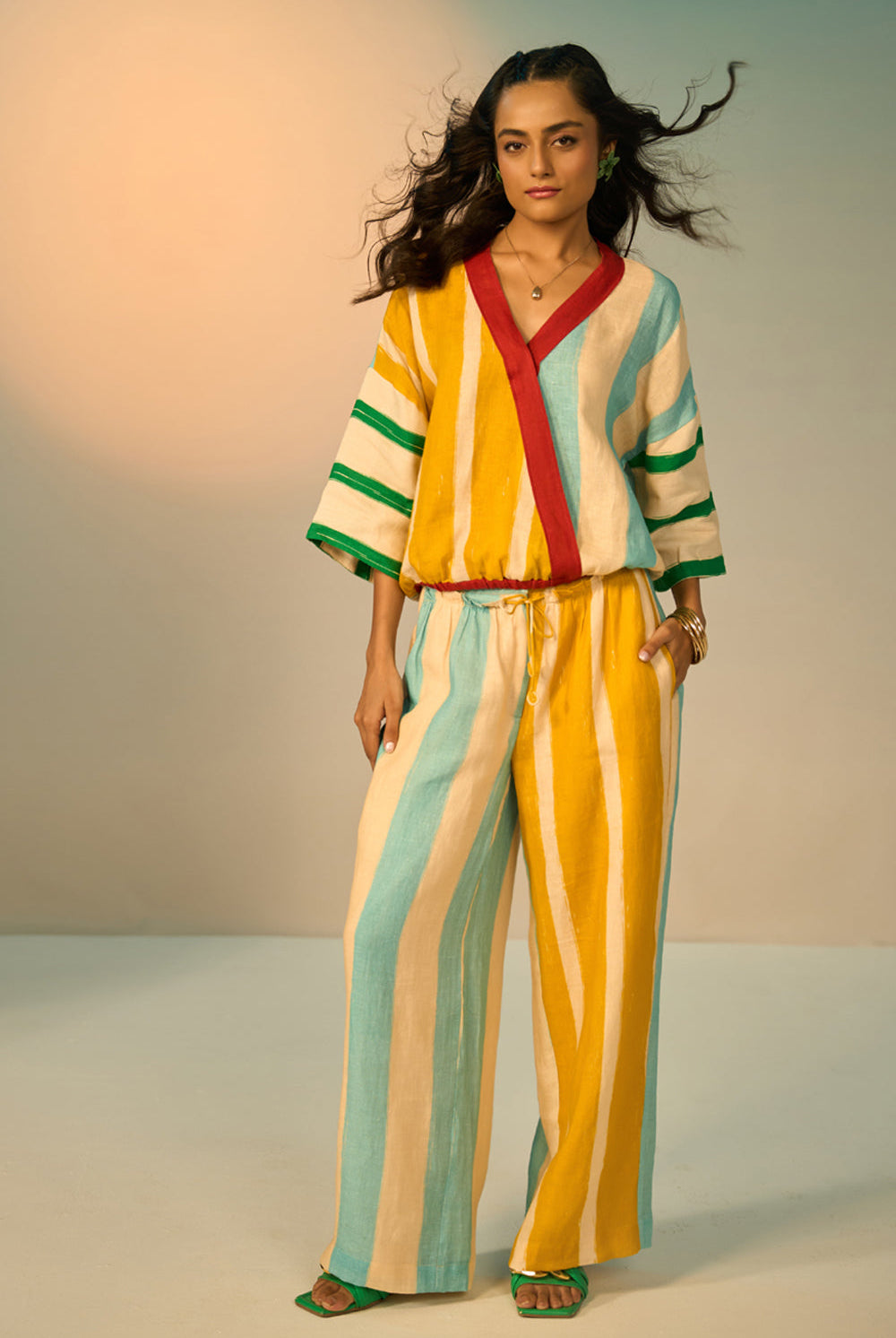 Woman wearing a colorful striped outfit against a neutral background