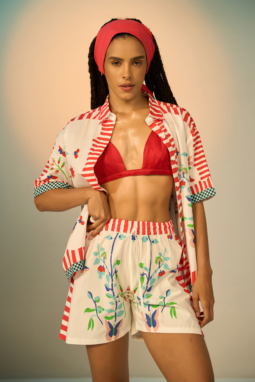 Woman wearing a ivory outfit set with a patterned shirt and shorts on a plain background