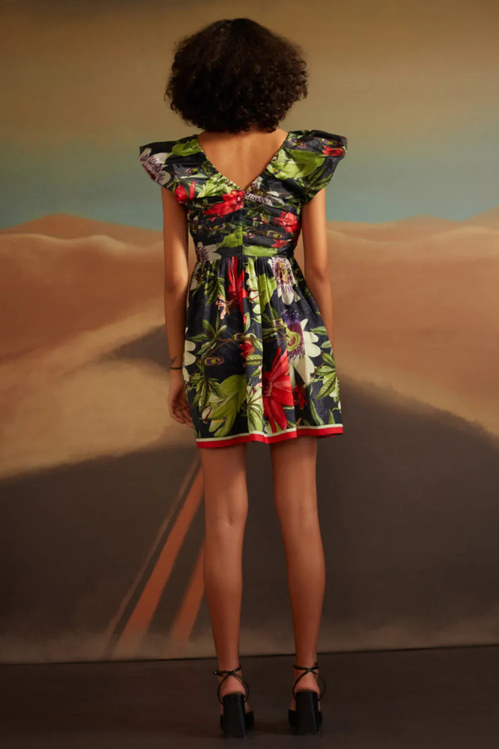 Person wearing a colorful floral dress standing against a desert landscape.