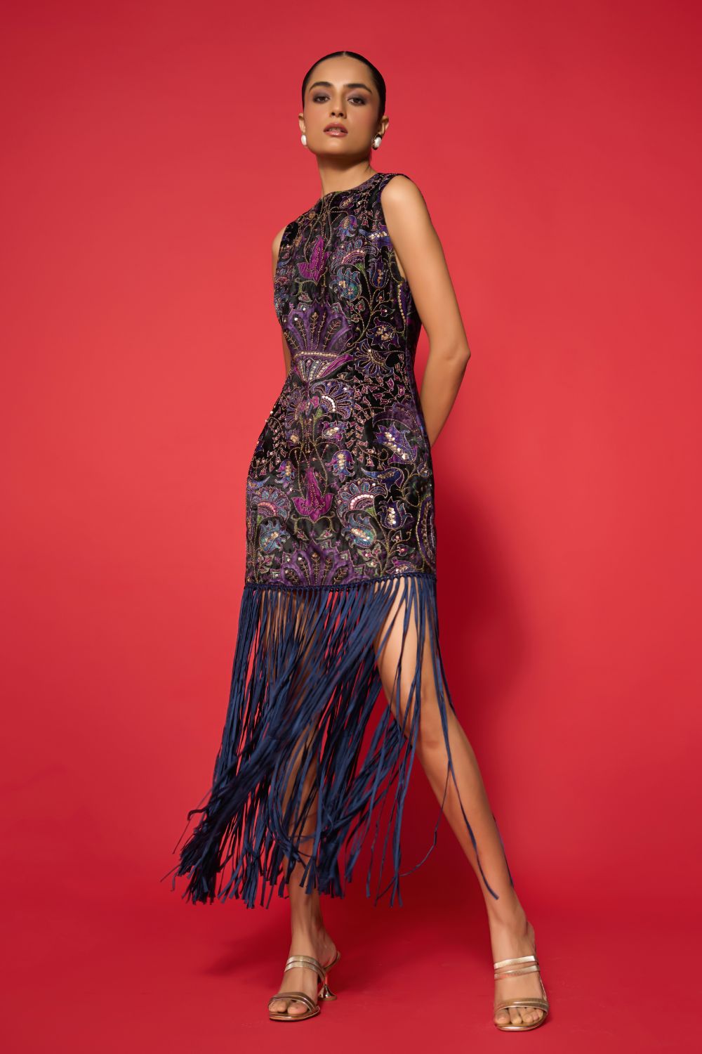 Woman wearing a black and purple patterned dress with fringe on a red background