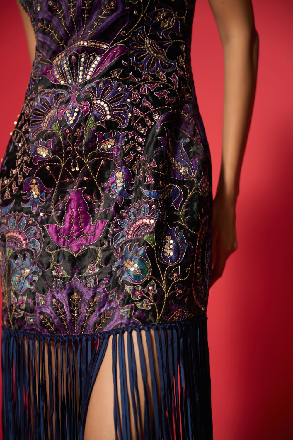 Elegant dress with intricate patterns and fringes on a red background