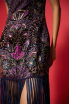 Elegant dress with intricate patterns and fringes on a red background