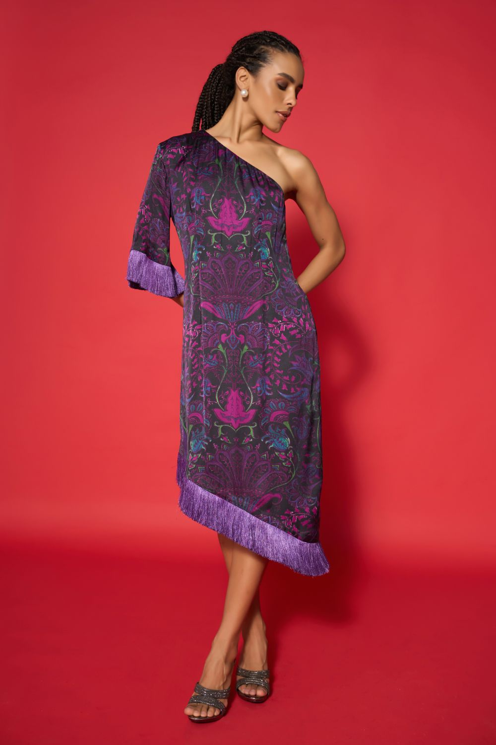 Woman wearing a purple one-shoulder dress with intricate patterns against a red background
