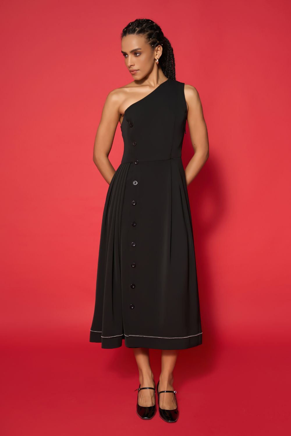 Woman wearing a black one-shoulder dress against a red background