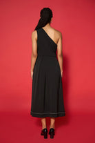 Woman wearing a black one-shoulder dress against a red background
