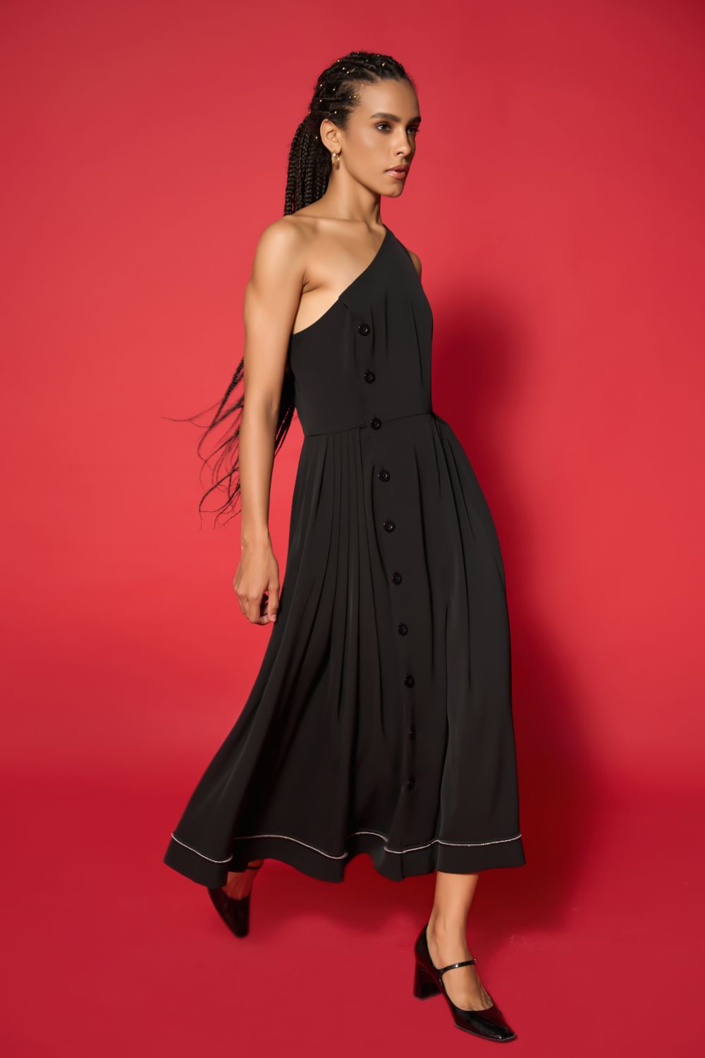 Woman wearing a black one-shoulder dress against a red background