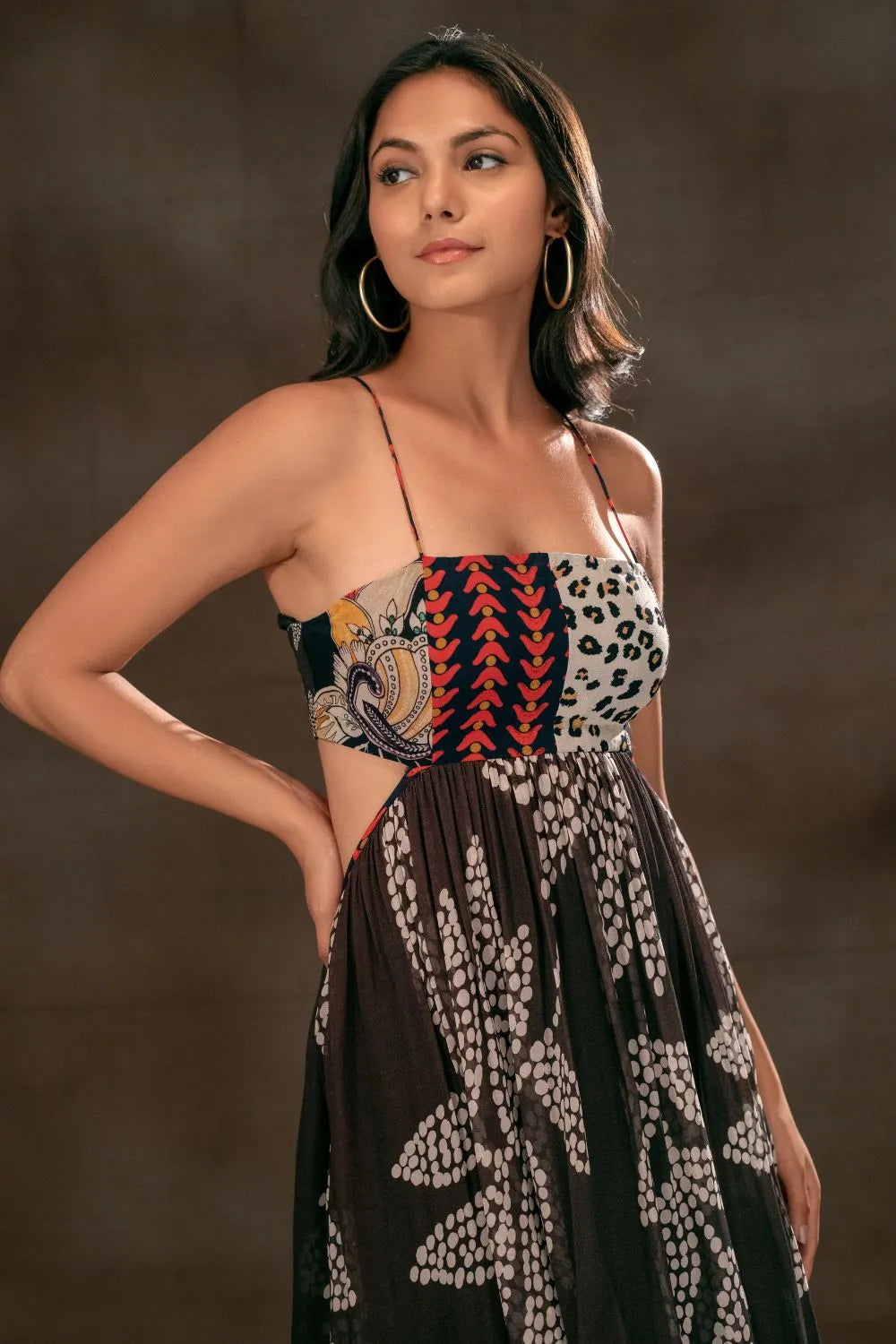 Woman wearing the Martha Spaghetti Dress, a women's black viscose georgette maxi dress featuring a multipatch and stippling print, delicate spaghetti straps and distinctive cutout detailing, styled for resort vacations, summer evenings and destination celebrations.