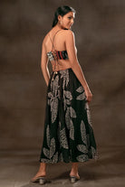 Back view of Devki Bhatt wearing the Martha Spaghetti Dress, a women's black viscose georgette maxi dress featuring a multipatch and stippling print, delicate spaghetti straps and distinctive cutout detailing, styled for resort vacations, summer evenings and destination celebrations.