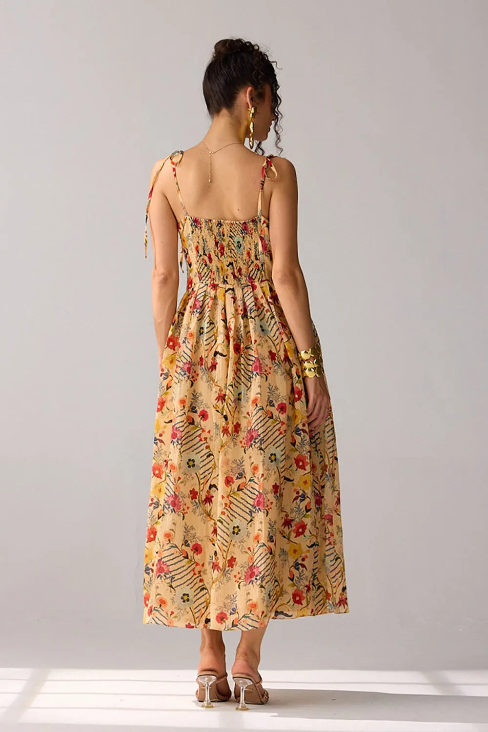 Back view of Dixie Dress women's beige chiffon maxi dress featuring a corset-fitted bodice, an elegant flowing skirt and an adjustable smocked back for a flattering fit, styled for summer getaways, resort dinners, luncheons and special occasions.