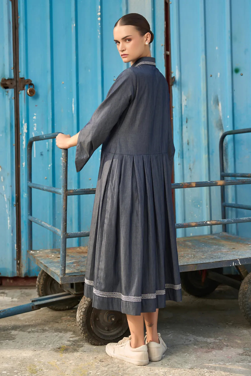 Back view of Elma Dress women's dark blue chambray midi dress featuring a structured shirt collar, button-down front, three-quarter sleeves with buttoned cuffs, a statement chest pocket with contrast stitching and a softly pleated skirt, styled for work meetings, casual outings and day-to-evening occasions.