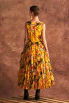 Woman wearing a yellow floral dress against a brown textured background