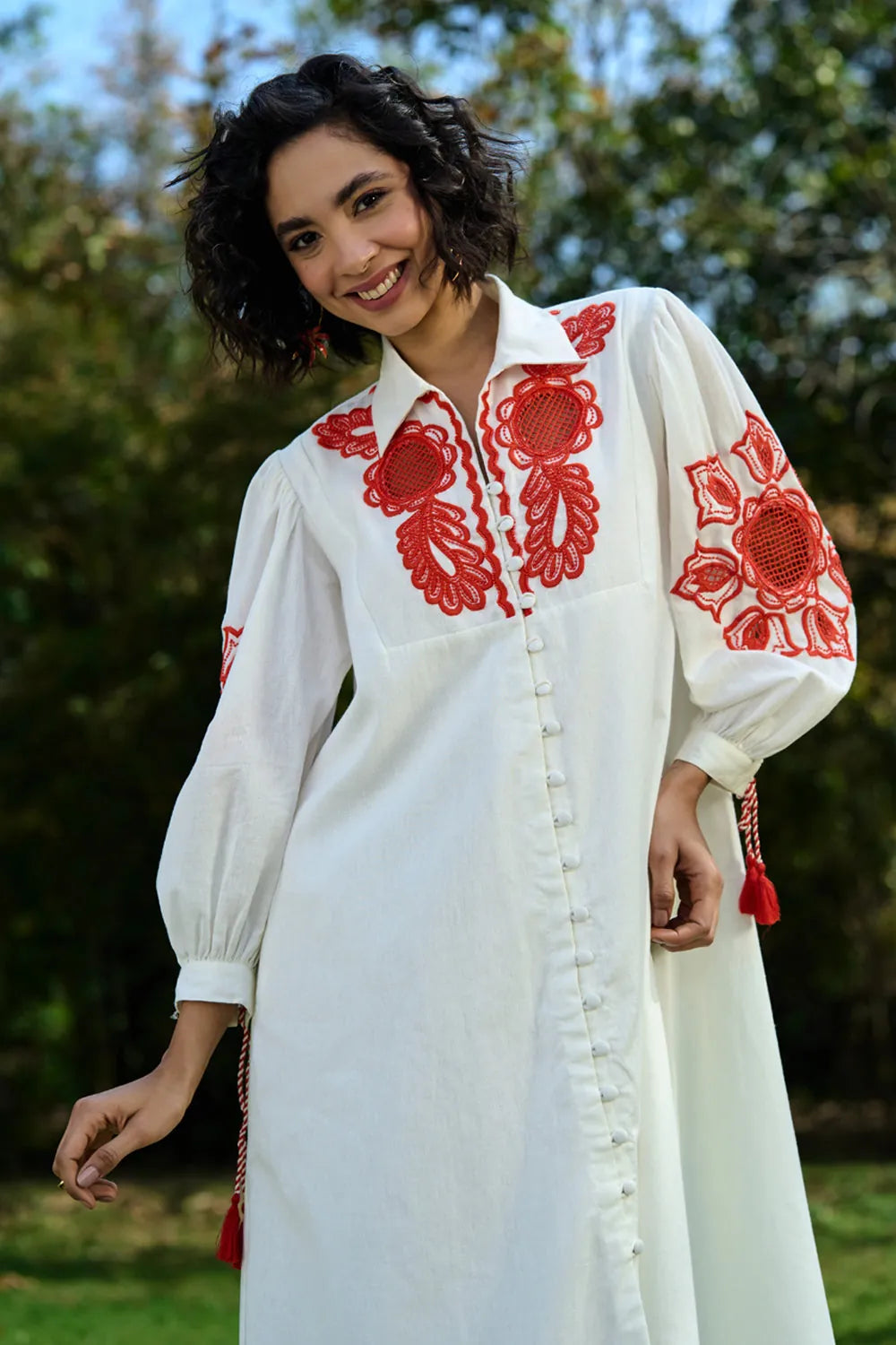 Closeup look of Ivar Embroidered Dress women's ivory cotton midi dress featuring intricate pearl cutwork embroidery on the sleeves, a relaxed silhouette and elegant handcrafted detailing, styled for summer brunches, daytime celebrations, garden gatherings and sophisticated casual occasions.