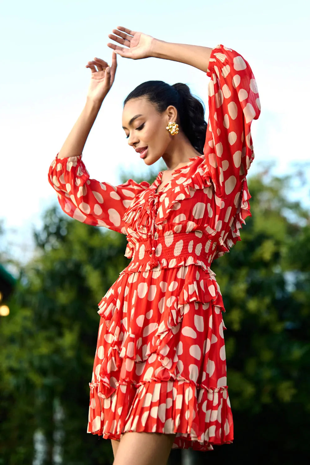 Full view of Izia Dress women's coral red Viscose Georgette mini dress featuring a playful white polka dot print, a tie-up neckline with beaded tassels and delicate ruffle detailing, styled for summer brunches, beach holidays, vacation outings and casual daytime gatherings.
