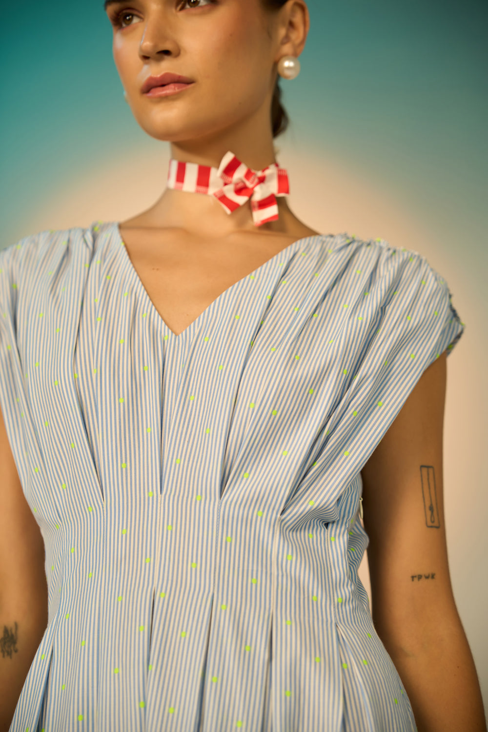 Woman wearing a blue and white striped dress with a red and white bow tie against a gradient background