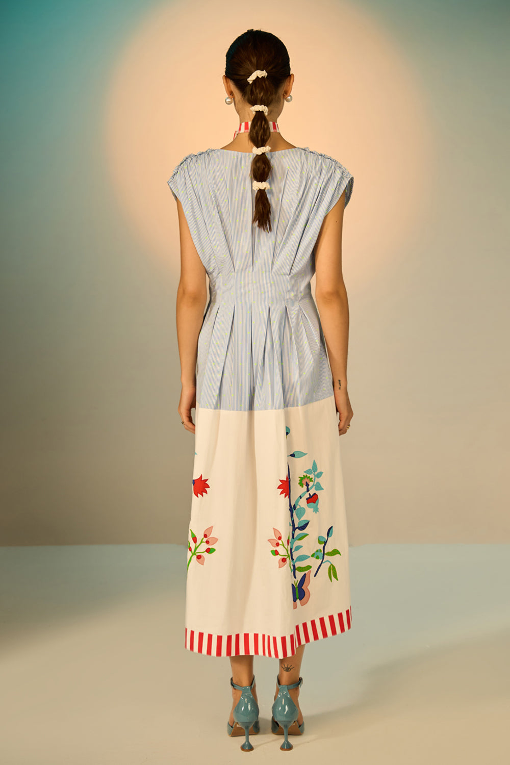 Woman wearing a dress with floral embroidery on a plain background