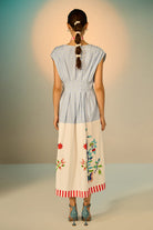 Woman wearing a dress with floral embroidery on a plain background