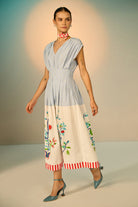 Woman wearing a two-tone dress with floral patterns on a neutral background