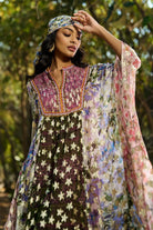 Woman wearing a colorful traditional outfit with a floral pattern in an outdoor setting.