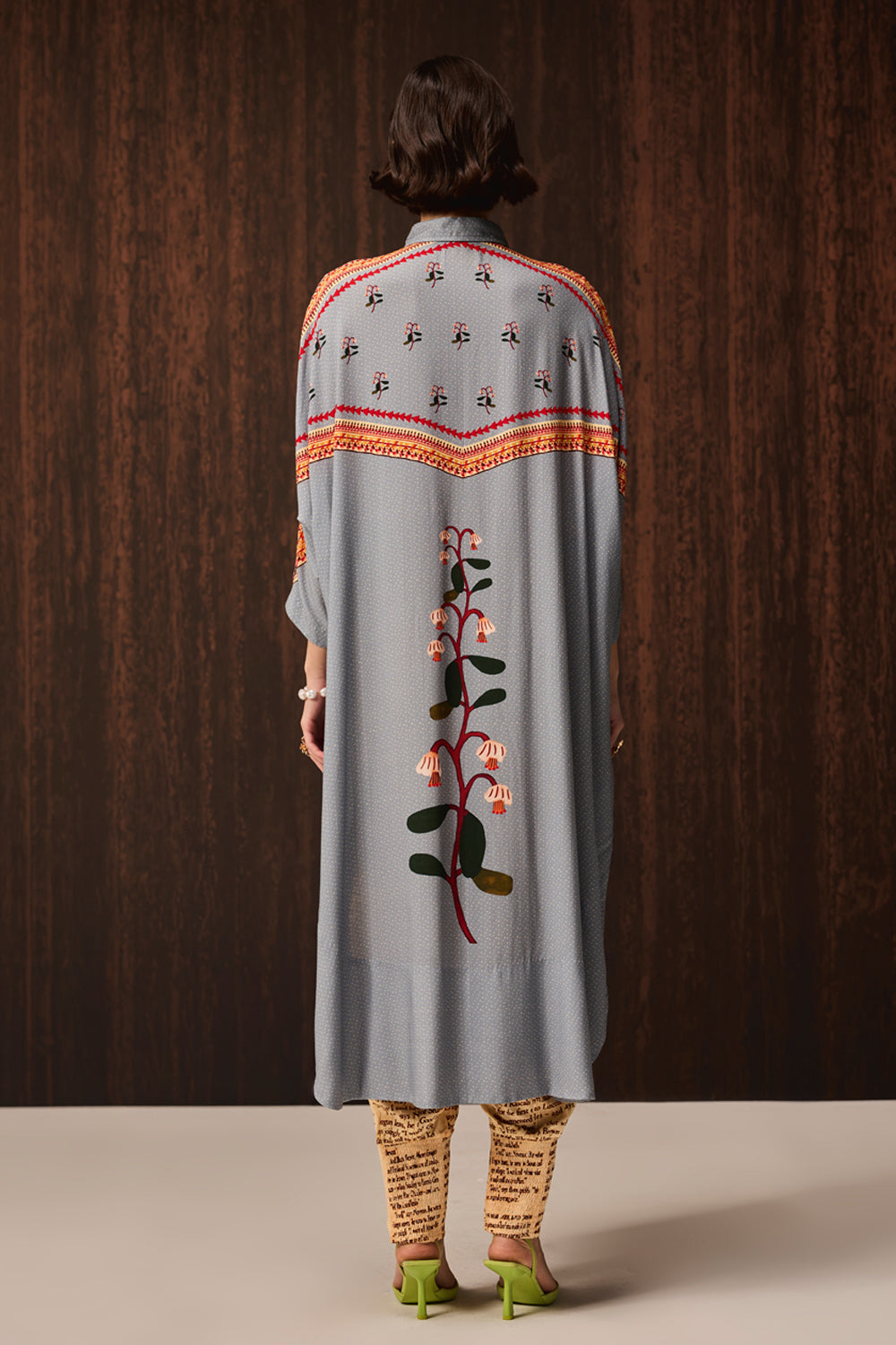 back view of Kori Embroidered Shirt With Pants women's pale blue Double Georgette co-ord set featuring an oversized shirt with tonal embroidery and matching newspaper-print jogger pants, combining a relaxed silhouette with an artistic statement design, styled for airport looks, resort lounging, travel days and casual outings.