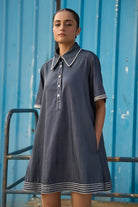 Full view of Rico Mini Dress women's dark blue chambray mini dress featuring a sharp pointed collar, short sleeves, a partial button-down front and contrast white stitching along the collar, sleeves, button placket and hem, finished with a loose flared A-line silhouette for casual outings, summer travel, relaxed daytime wear and casual dinners.