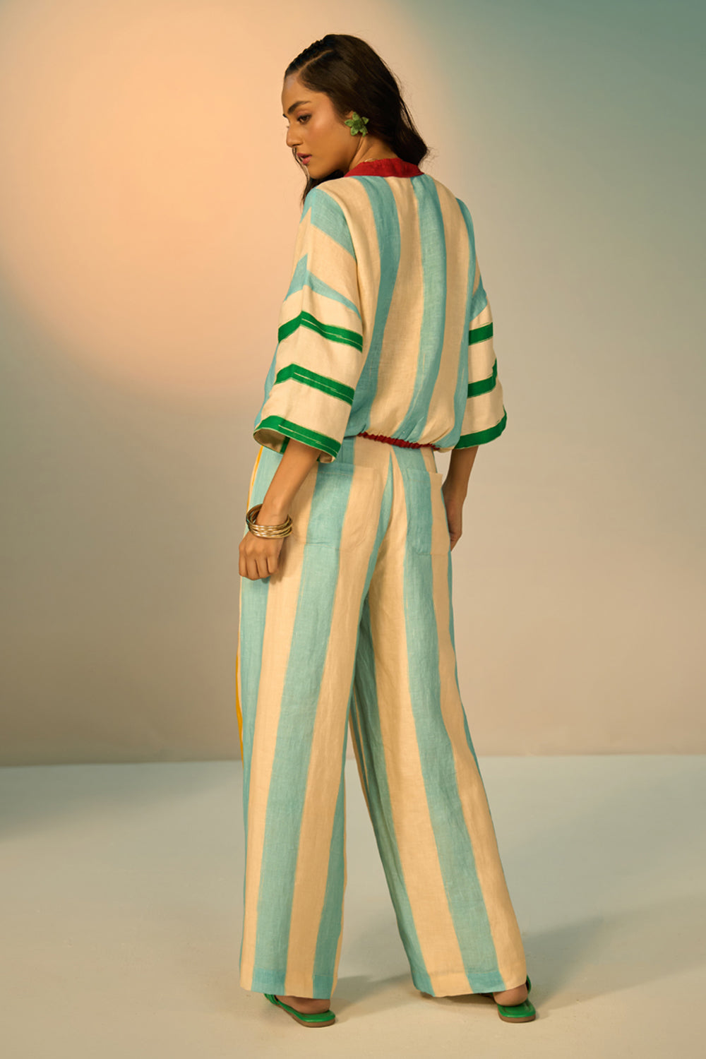 Back view of woman wearing a striped outfit set with a neutral background