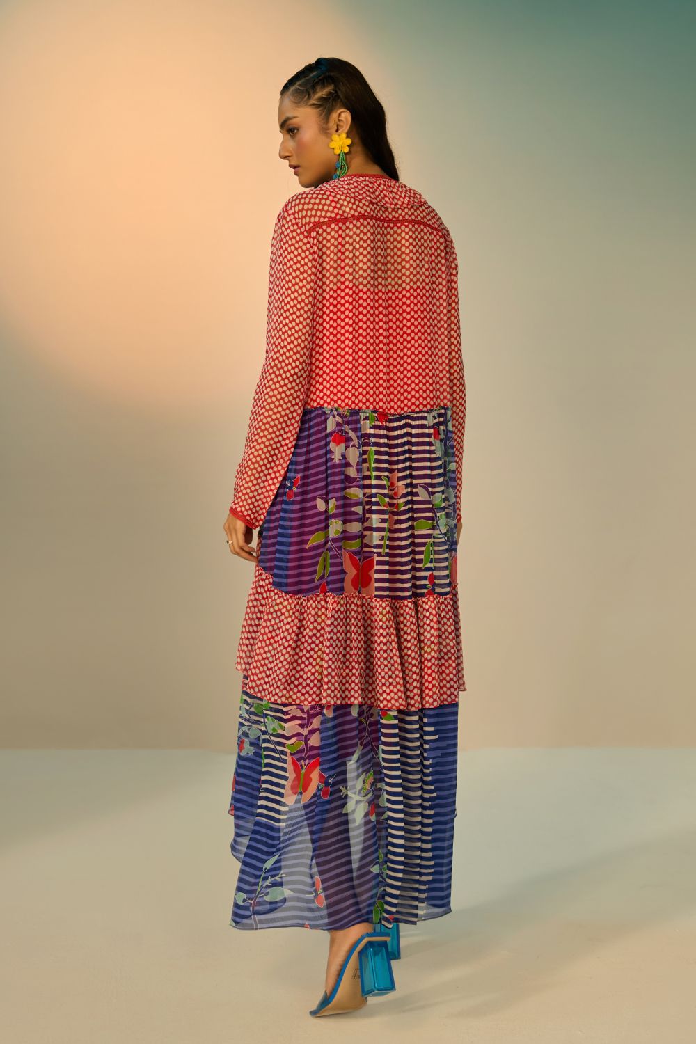 Back view of a woman wearing a red and blue striped dress with a clean background