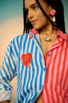 Woman wearing a colorful co-ord set with a blue and pink striped shirt with a heart design.