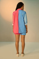 back view of a woman wearing a colorful co-ord set with a blue and pink striped shirt and shorts.