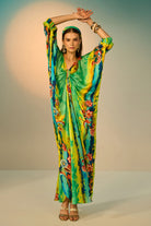 A woman modeling a vibrant, multicolored kaftan dress with a tie-dye pattern in multicolor, styled with a matching headband and gold accessories against a neutral studio backdrop.